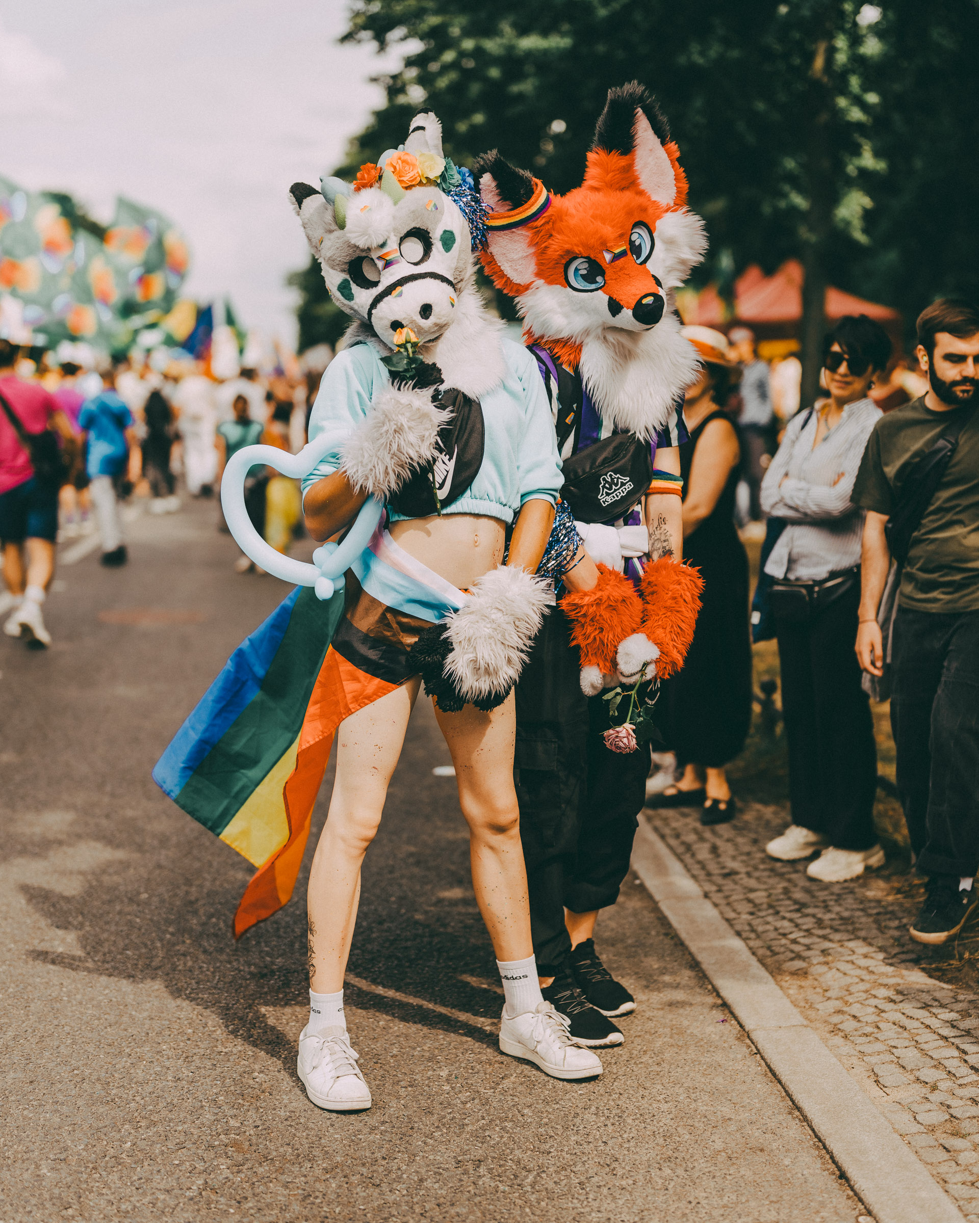 Fursuits und Regenbogenflagge bei einer Parade. 
