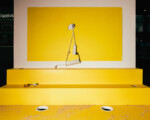 Werkzeug und Kabel auf gelbem Podest vor gelber Wand.
