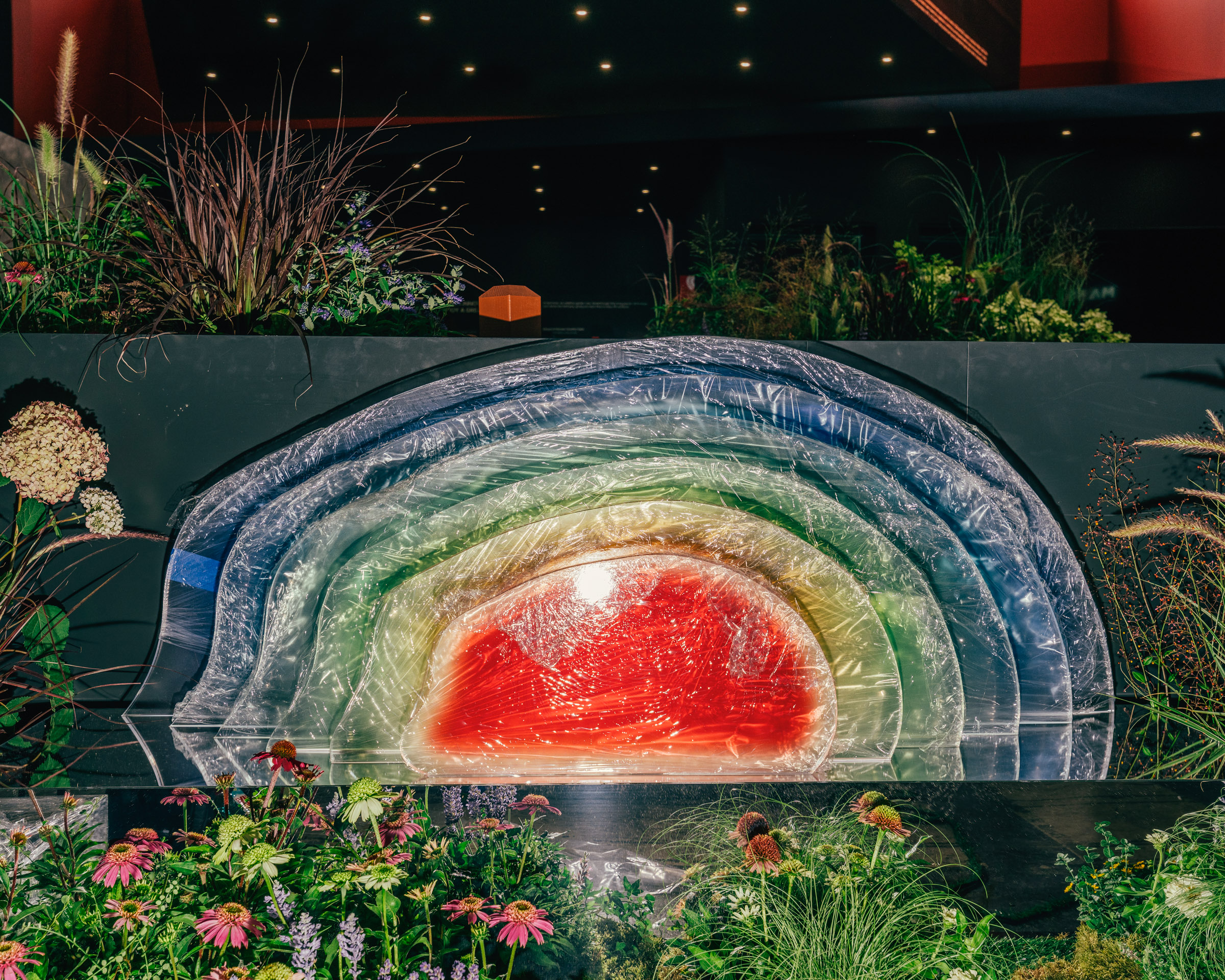 Regenbogen-Skulptur mit Blumen und Gräsern. 