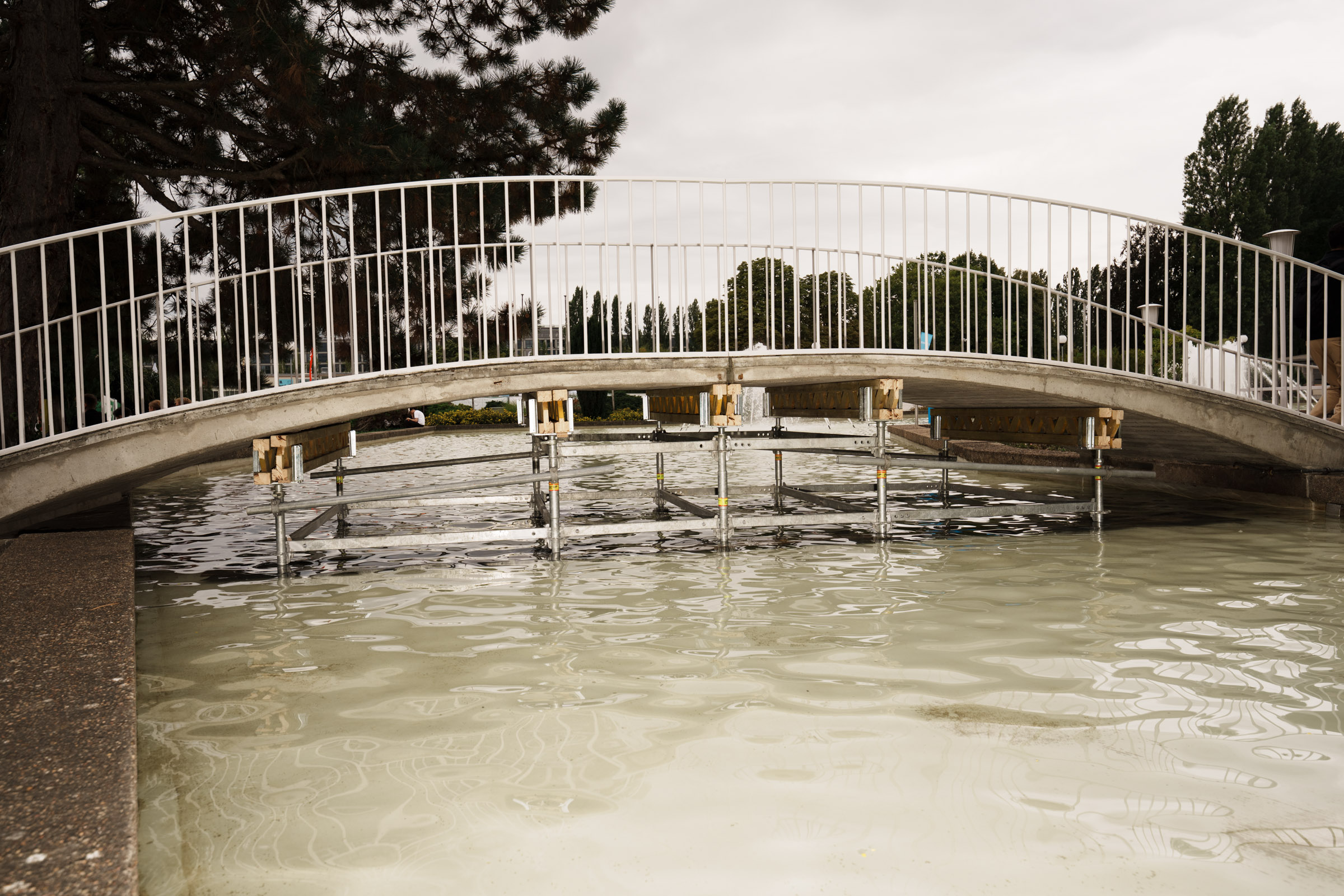 Brücke über Wasser mit Gerüst und Bäumen. 