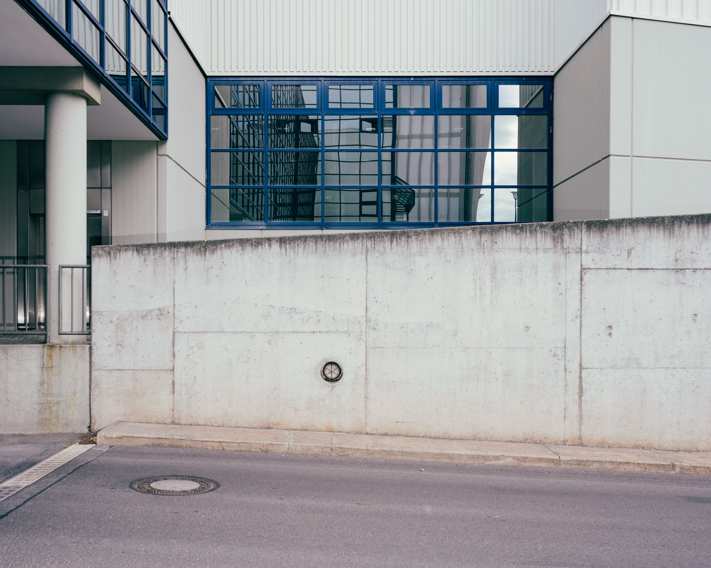 Betonwand vor modernem Gebäude mit Fenstern. 