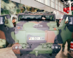 Militärfahrzeug mit Personen im Inneren und Hintergrund.