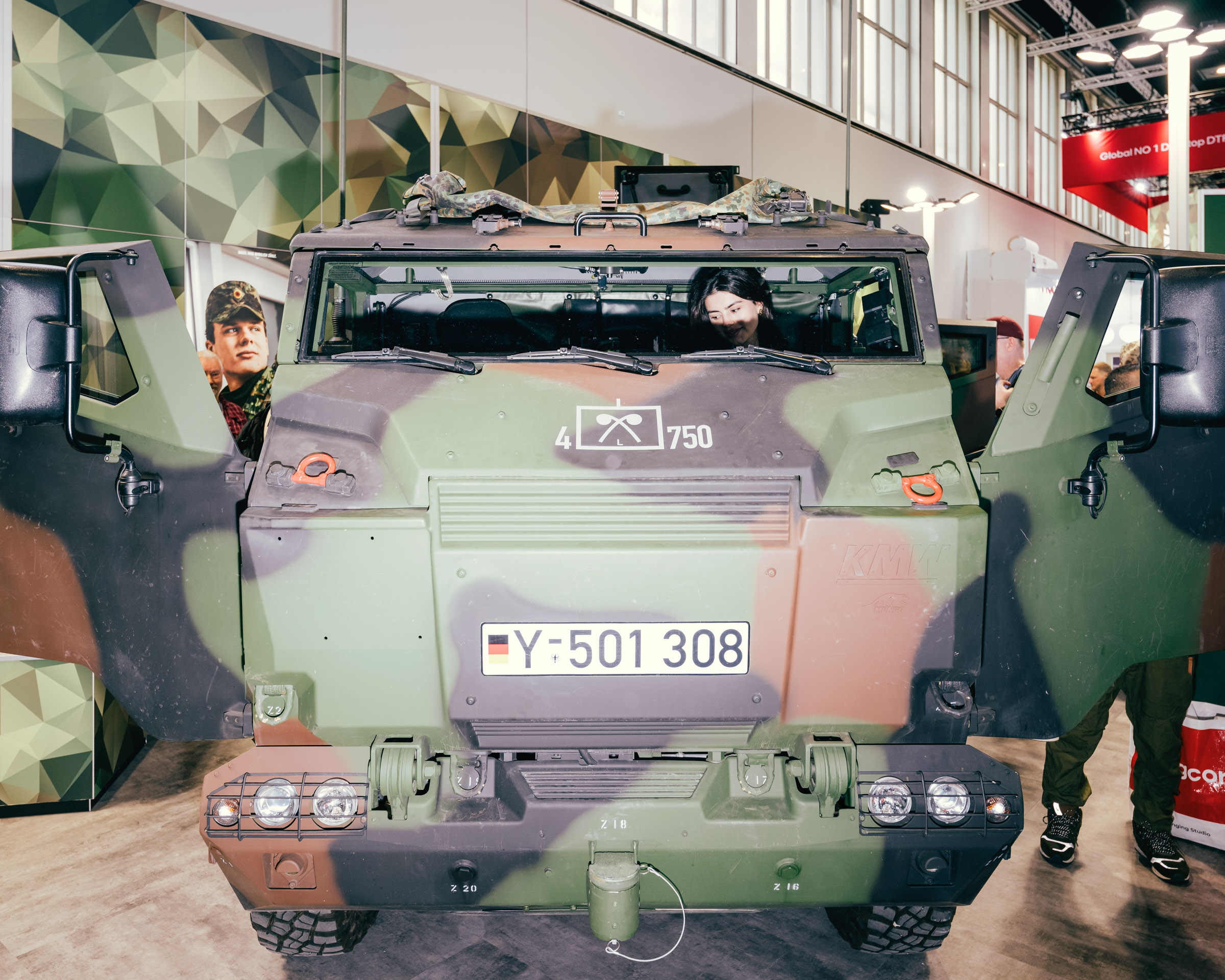 Militärfahrzeug mit Personen im Inneren und Hintergrund. 
