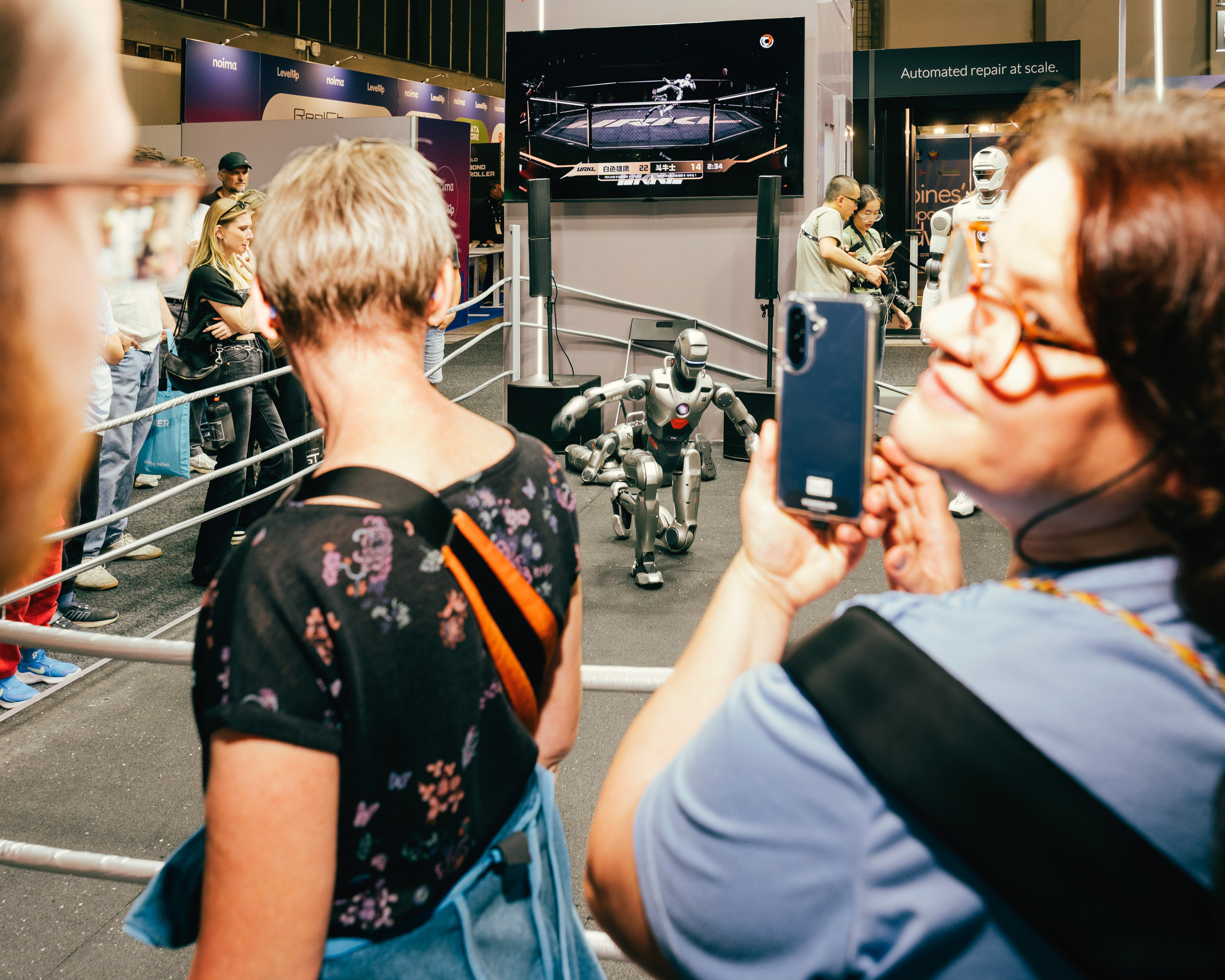 Menschen fotografieren Roboter bei einer Messe. 