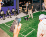 Roboter-Fußballspiel mit Zuschauern und Handy-Aufnahme.