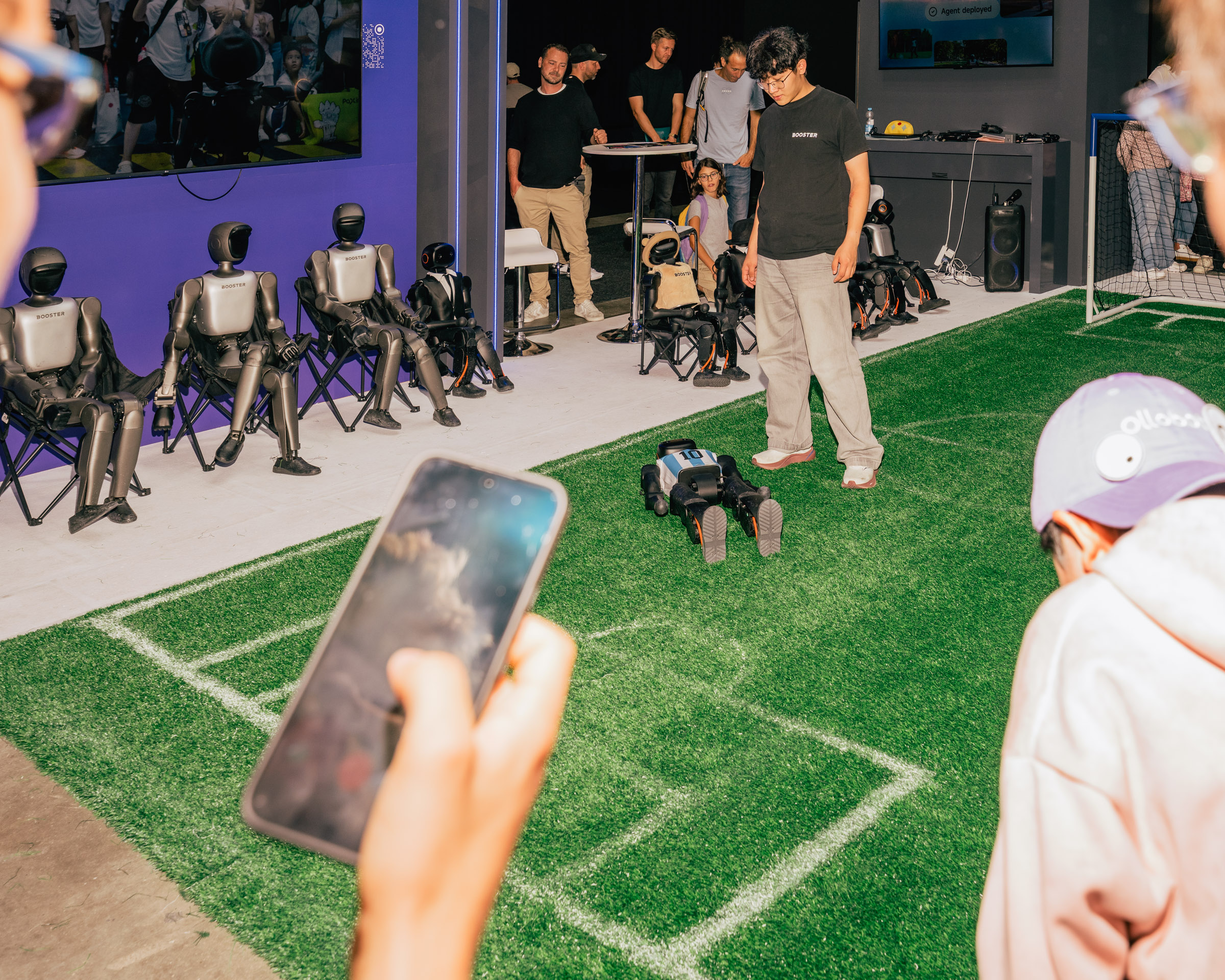 Roboter-Fußballspiel mit Zuschauern und Handy-Aufnahme. 