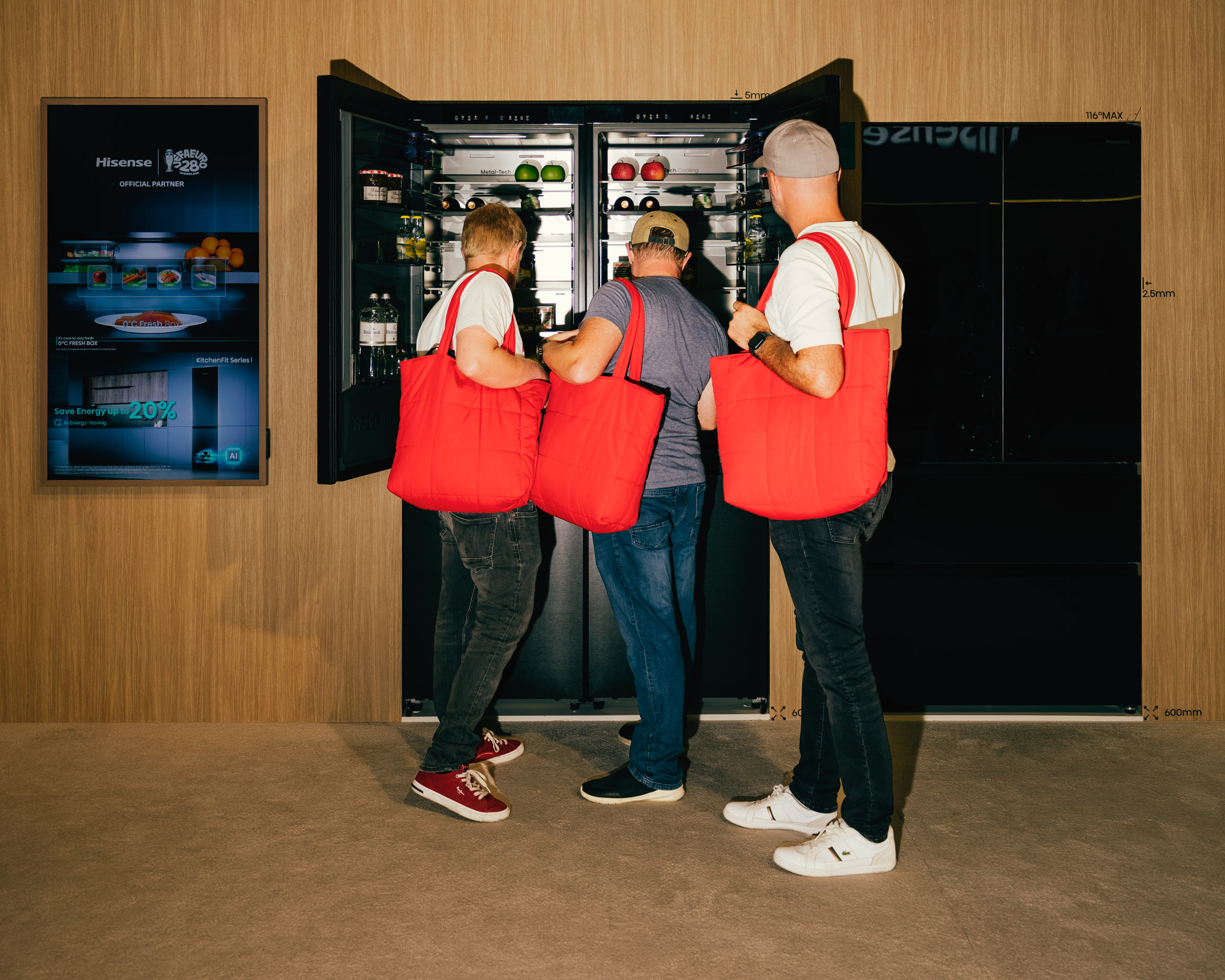 Männer mit roten Taschen betrachten Kühlschrank. 
