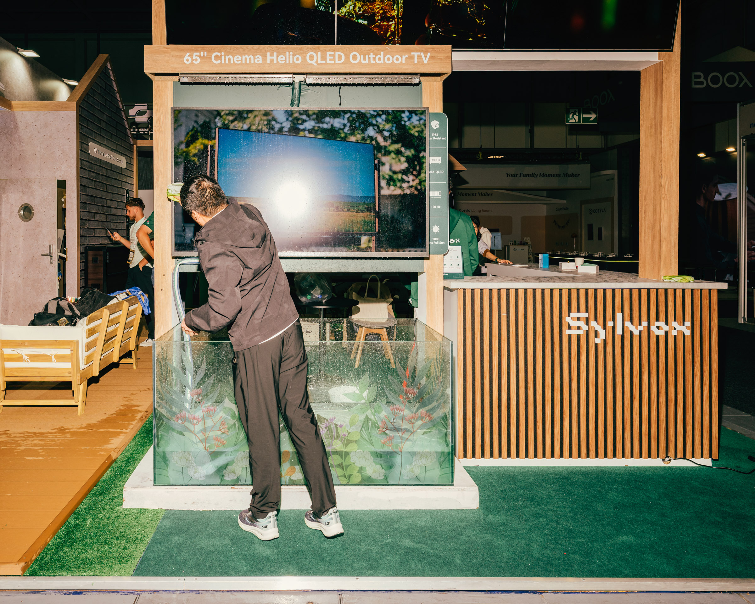 Mann vor großem Outdoor-Fernseher mit Wasserbecken. 