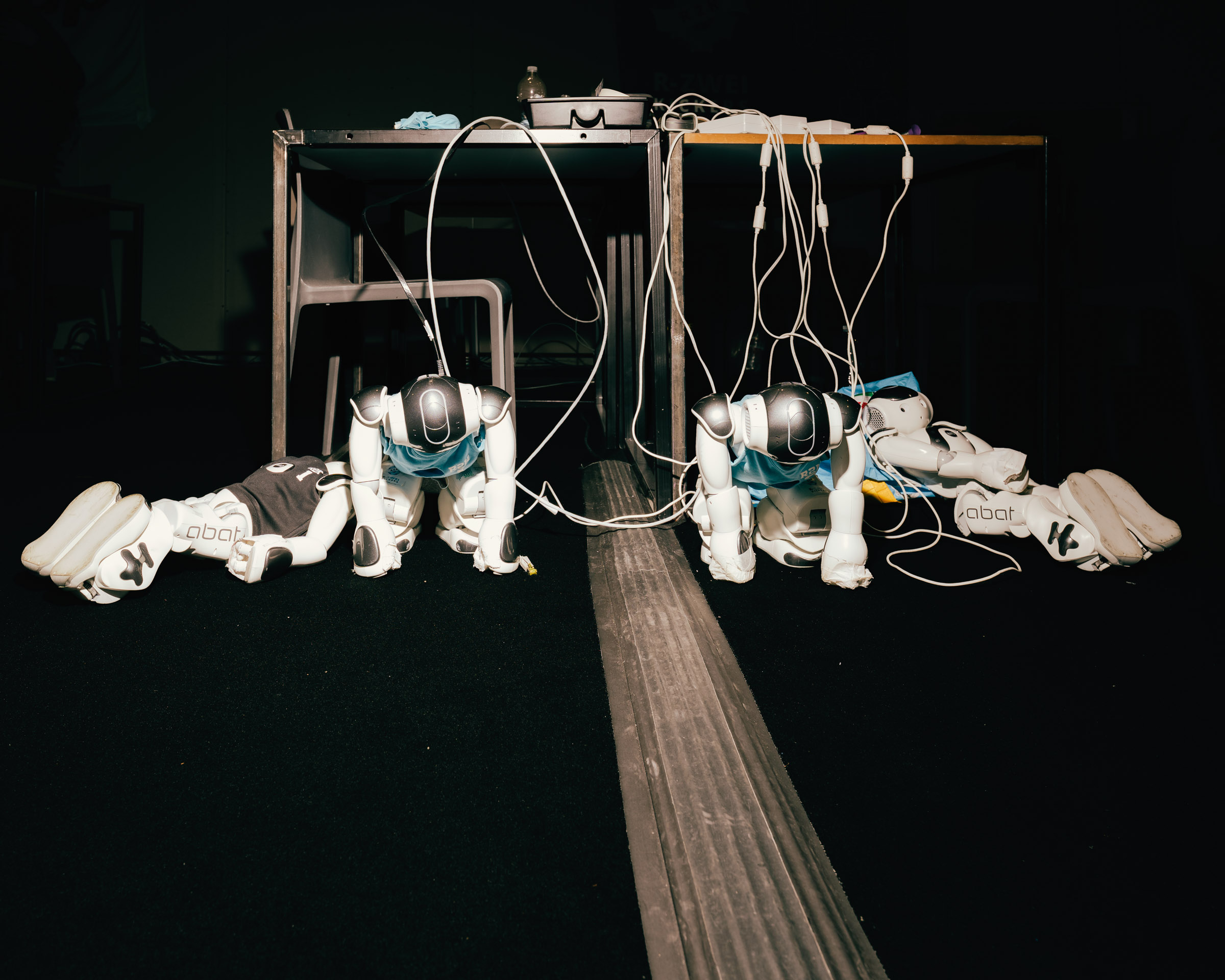 Zwei Roboter liegen am Boden, verbunden mit Kabeln. 