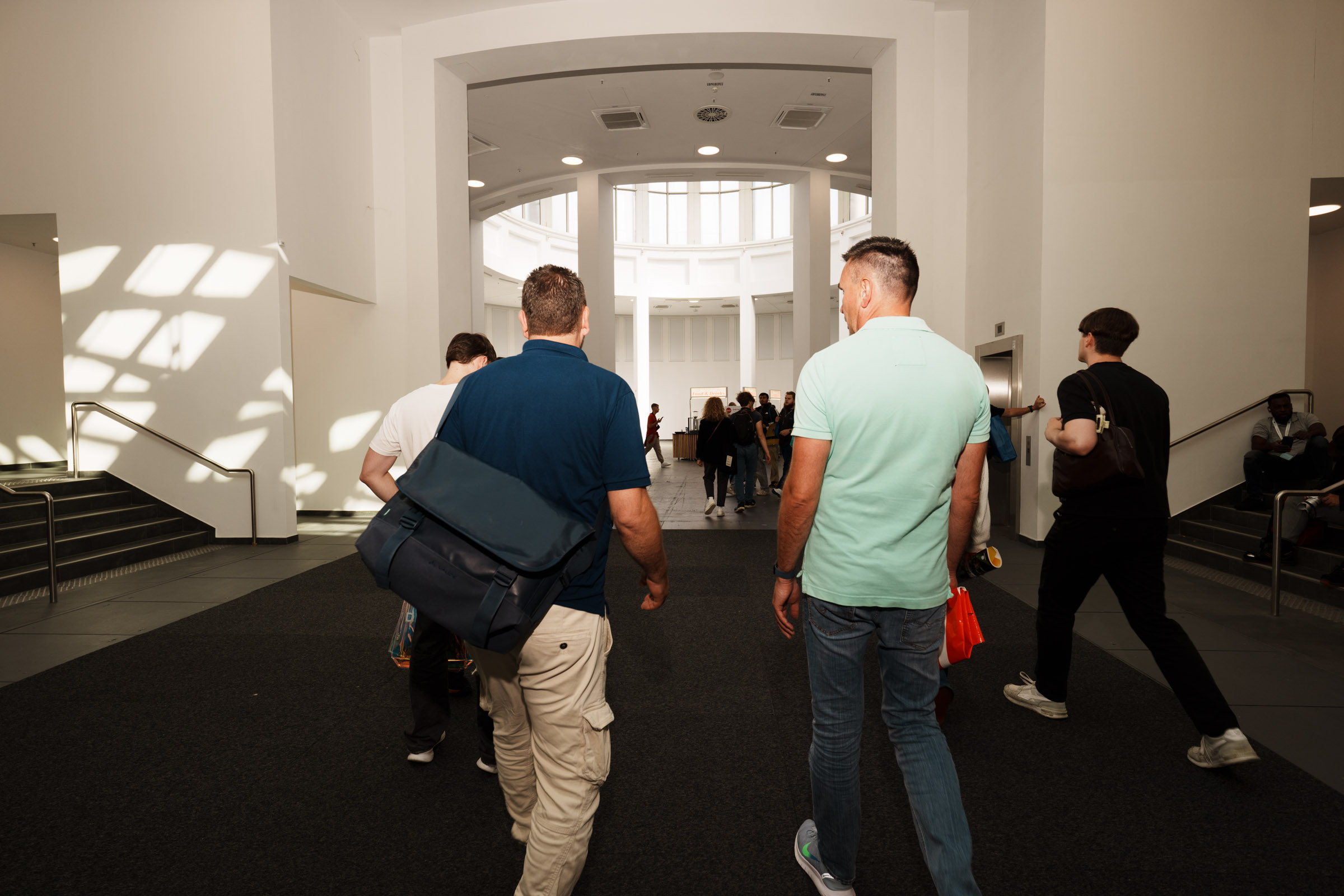 Menschen gehen durch eine helle, moderne Halle. 
