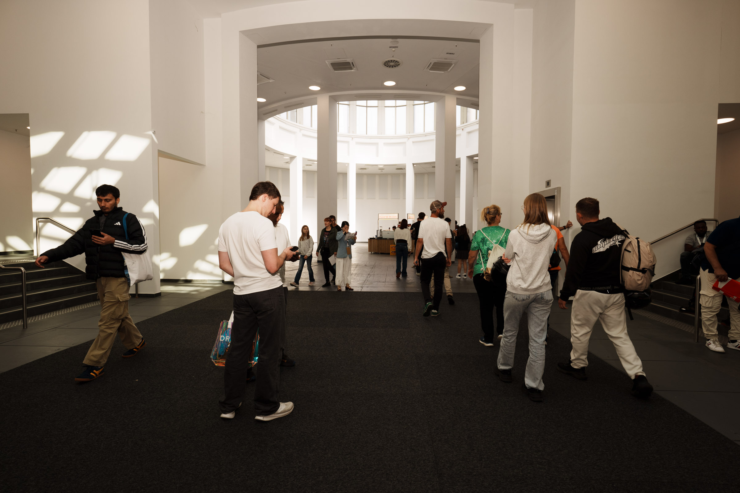 Menschen gehen durch eine helle, moderne Halle. 