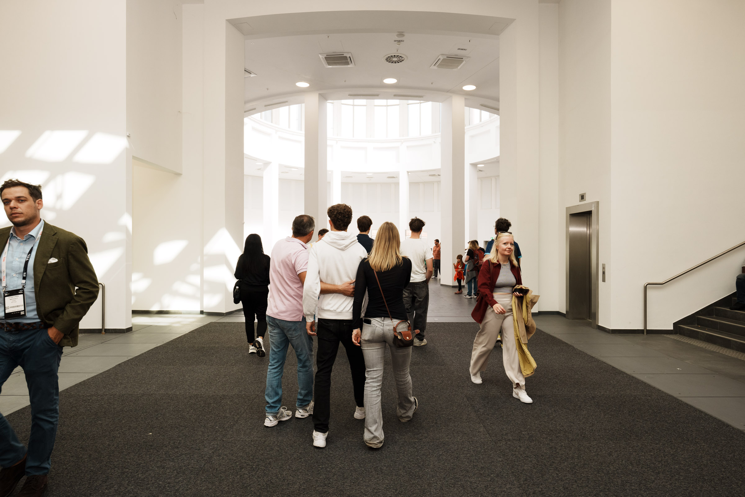 Menschen gehen durch eine helle, moderne Halle. 