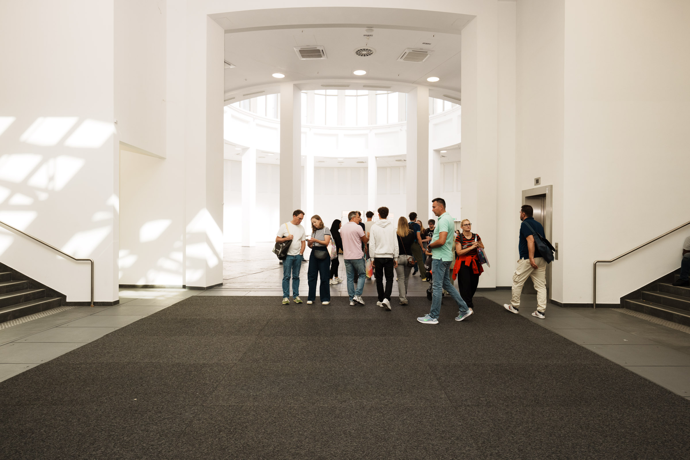 Menschen gehen durch eine helle, moderne Eingangshalle. 